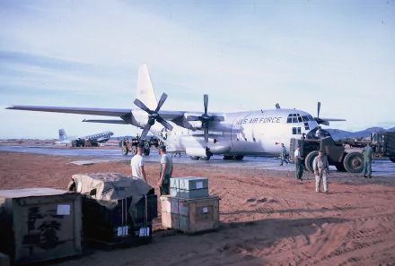 HD desktop wallpaper featuring a military Lockheed C-130 Hercules aircraft on a desert airstrip with personnel and cargo nearby.