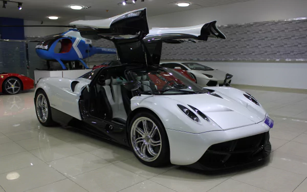 White Pagani Huayra sports car with butterfly doors open in a showroom, glossy floor reflection — 4K Ultra HD PC desktop wallpaper and background.