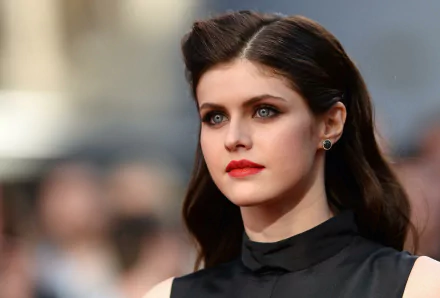 An HD desktop wallpaper of Alexandra Daddario, showcasing her with flowing dark hair and elegant makeup, against a blurred background.