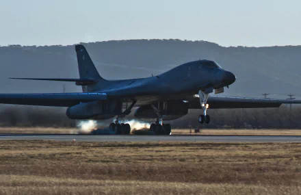 A Rockwell B-1 Lancer military bomber aircraft landing on a runway, captured in high-definition as a PC desktop wallpaper and background.