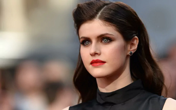 An HD desktop wallpaper of Alexandra Daddario, showcasing her with flowing dark hair and elegant makeup, against a blurred background.