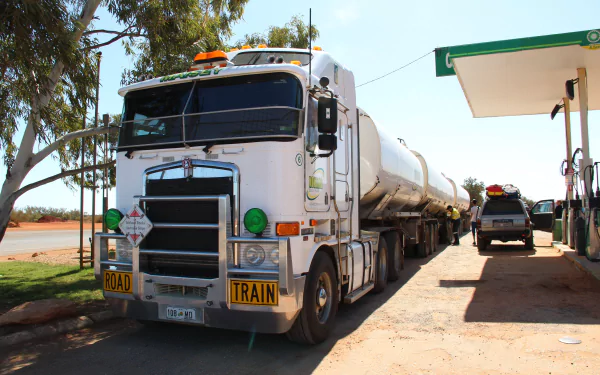 5K Ultra HD desktop wallpaper of a white Kenworth road-train tanker truck parked at a rural fuel station beneath a clear sky.