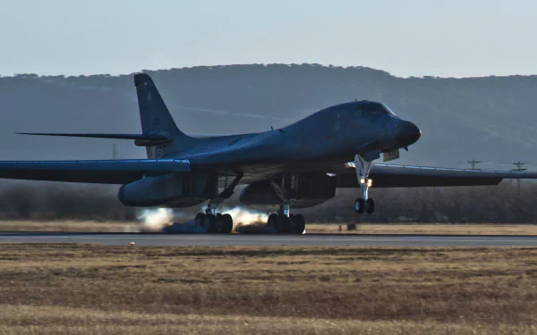A Rockwell B-1 Lancer military bomber aircraft landing on a runway, captured in high-definition as a PC desktop wallpaper and background.
