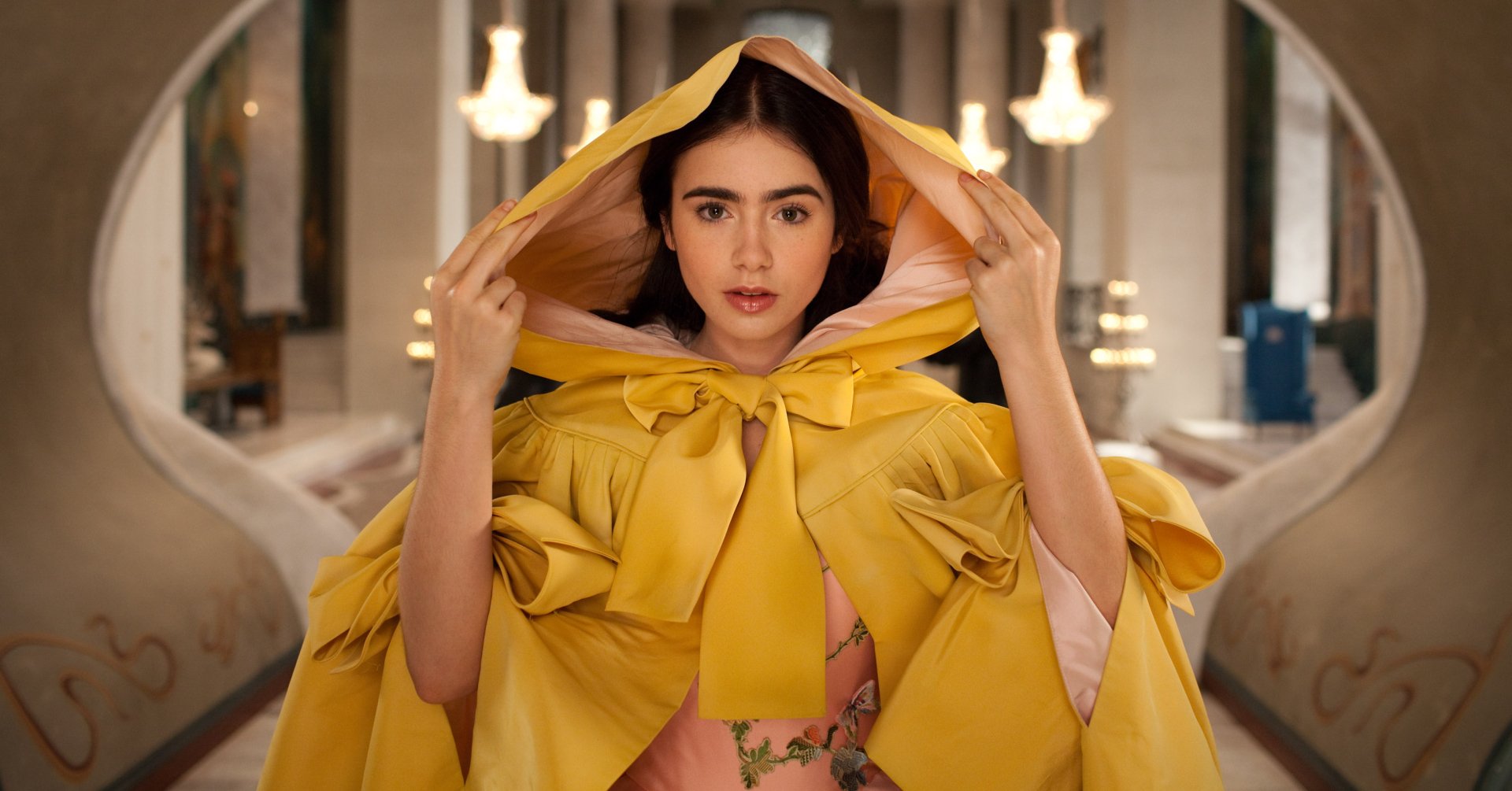 Lily Collins as the enchanting character in Mirror Mirror, adorned in a striking yellow cloak, captures a magical moment in this HD wallpaper.