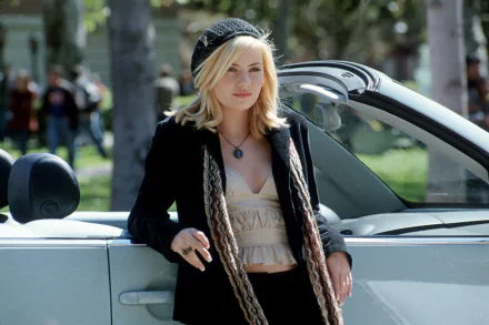 Elisha Cuthbert in a scene from the movie The Girl Next Door, leaning against a car, exuding a laid-back yet stylish vibe. A vibrant HD desktop wallpaper.