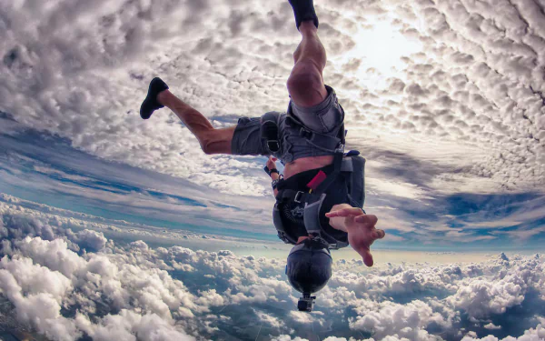 A skydiver captured mid-freefall above a sea of clouds, with dynamic clouds and expansive sky in this 4K Ultra HD sports desktop wallpaper and background.