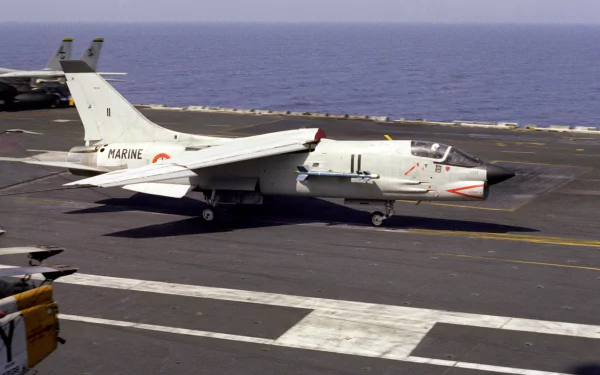 HD desktop wallpaper featuring a military Vought F-8 Crusader jet preparing for takeoff from an aircraft carrier at sea.