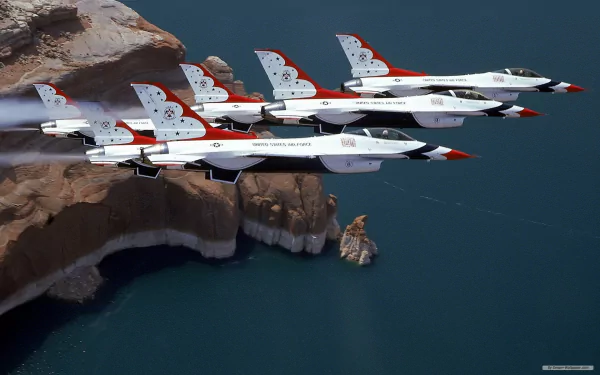 HD PC desktop wallpaper/background: military U.S.A.F. Thunderbirds jets in tight formation flying low over rocky cliffs and deep blue water.