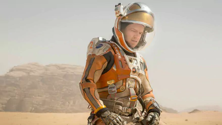 HD desktop wallpaper featuring Matt Damon in his spacesuit from the movie The Martian, set against a barren, rocky desert landscape.