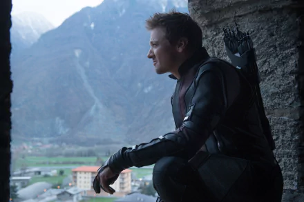 Hawkeye, played by Jeremy Renner, gazes out from a rocky ledge in a scene from *Avengers: Age of Ultron*, set against a breathtaking mountain backdrop. 4K Ultra HD wallpaper.