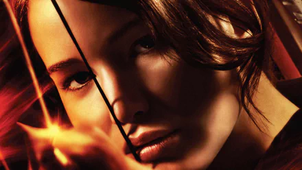 Close-up of Katniss Everdeen, portrayed by Jennifer Lawrence, with a bow, showcasing intensity from *The Hunger Games*. HD wallpaper captures a dramatic moment in the film.