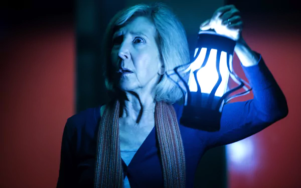 Lin Shaye from Insidious: Chapter 3 holding a glowing lantern in a dark, eerie setting, captured in a 4K Ultra HD PC desktop wallpaper and background.