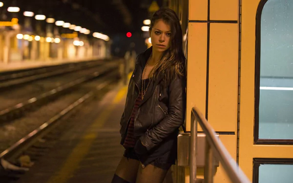 HD PC wallpaper: Orphan Black TV show scene — a lone woman in a leather jacket leans against a dim subway platform.