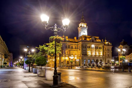Photography, light — 2K Quad HD PC desktop wallpaper/background: illuminated historic town hall at night with glowing street lamps and wet reflective pavement highlighting architectural details.