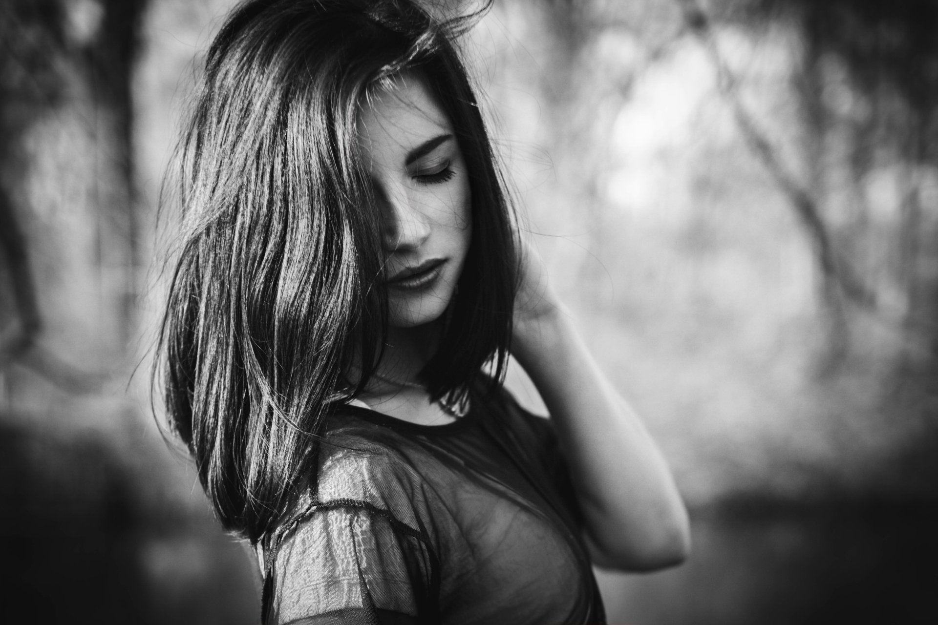 A striking black and white image of a brunette woman, exuding a moody atmosphere, captured in high-resolution, making it a captivating desktop wallpaper or background.
