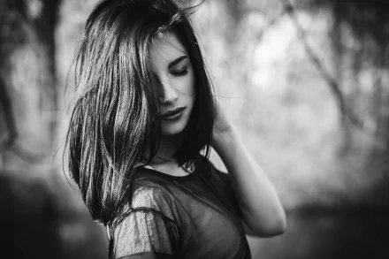 A striking black and white image of a brunette woman, exuding a moody atmosphere, captured in high-resolution, making it a captivating desktop wallpaper or background.