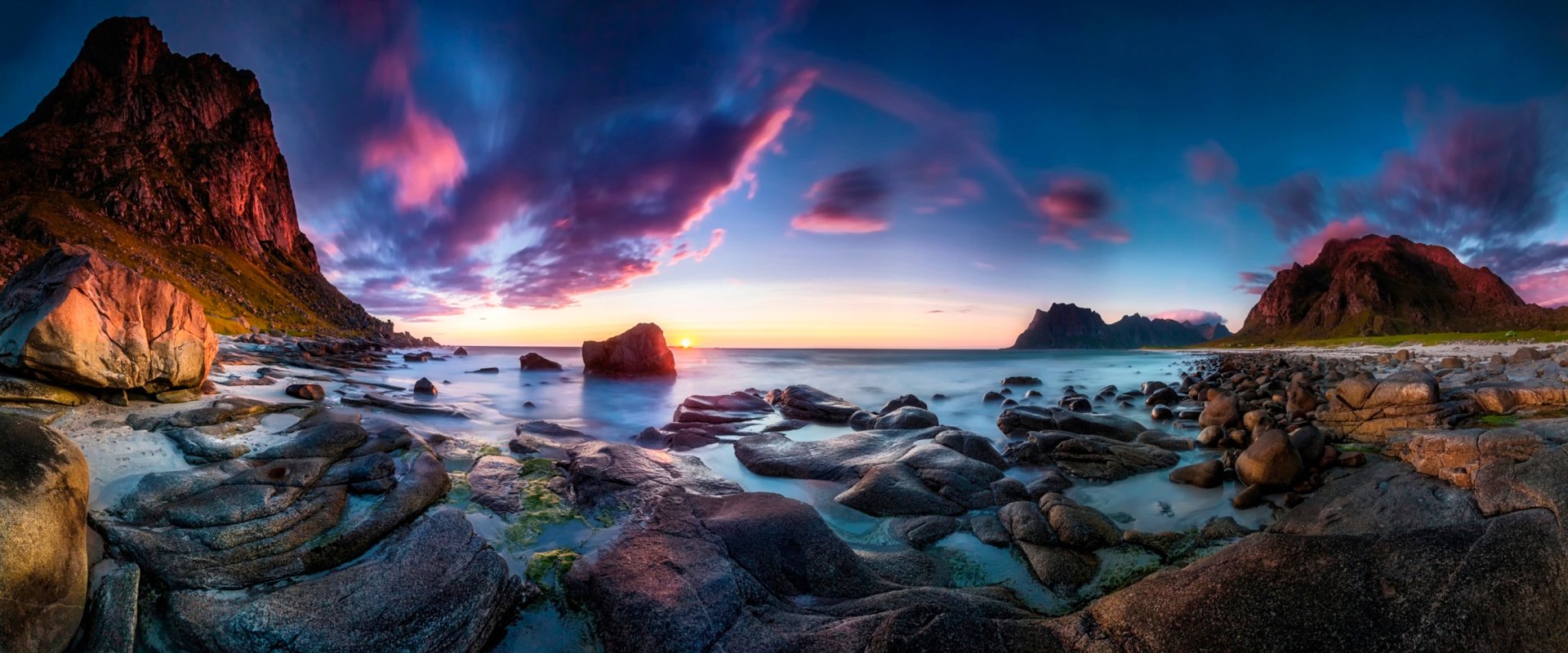 HD desktop wallpaper showcasing a vibrant coastal landscape at sunset, with rocky shores, calm waters, and dramatic clouds highlighting the natural scenery.