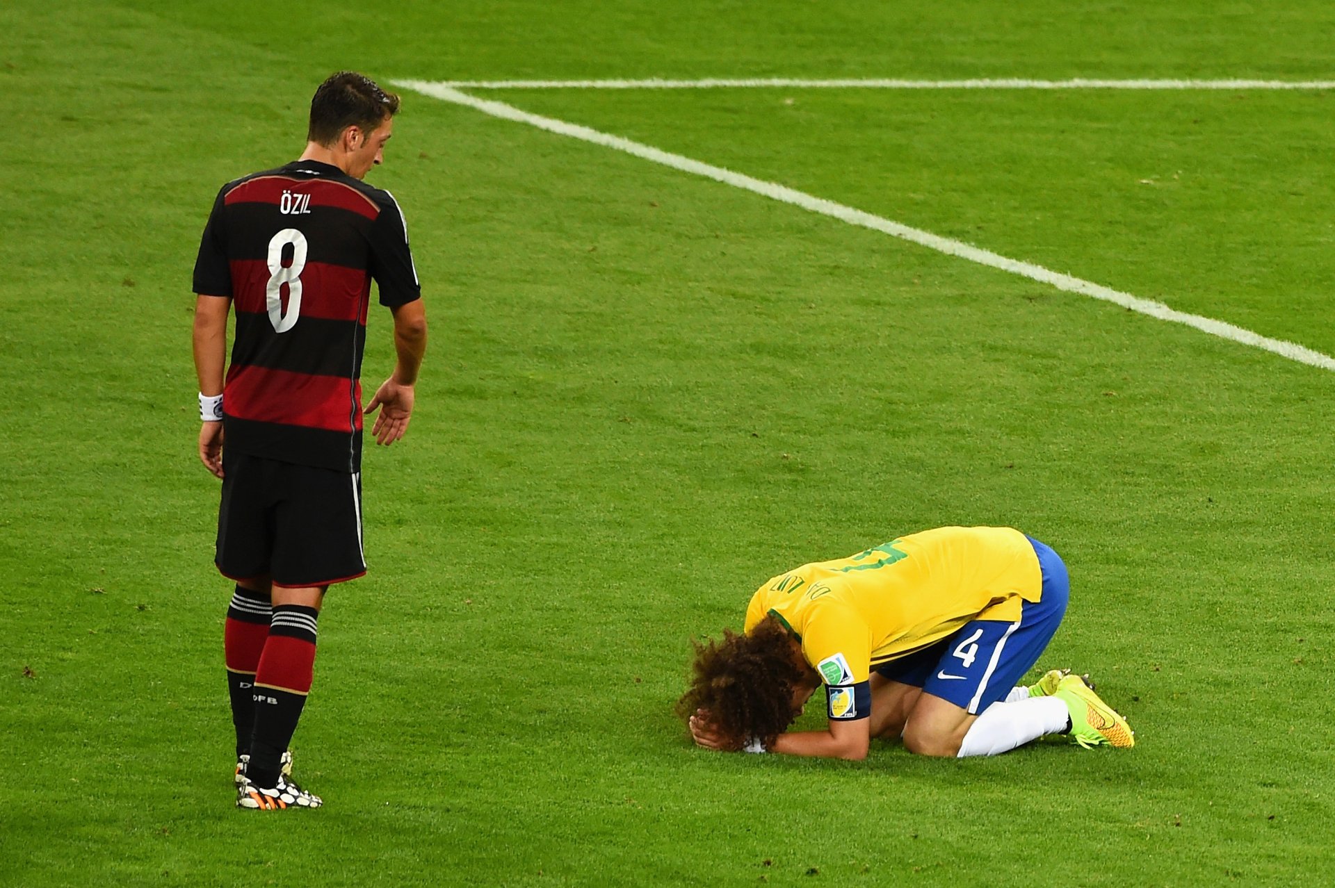 2K Quad HD PC desktop wallpaper — soccer sports scene: a player in yellow kneels head-down on the pitch while an opponent in black-and-red stands nearby.