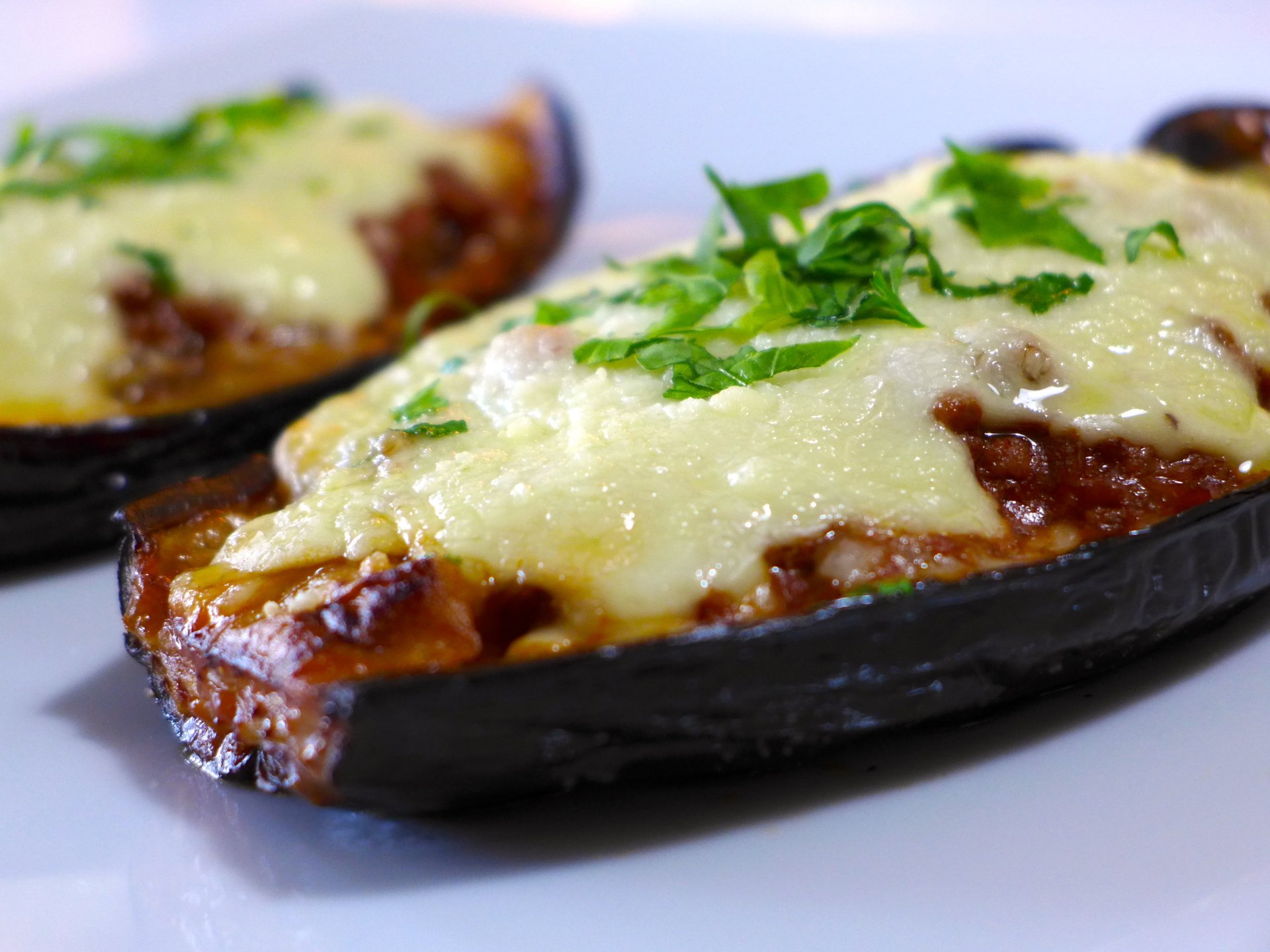 Close-up of baked eggplant halves topped with melted cheese and fresh herbs, presented as an HD PC desktop wallpaper and background.