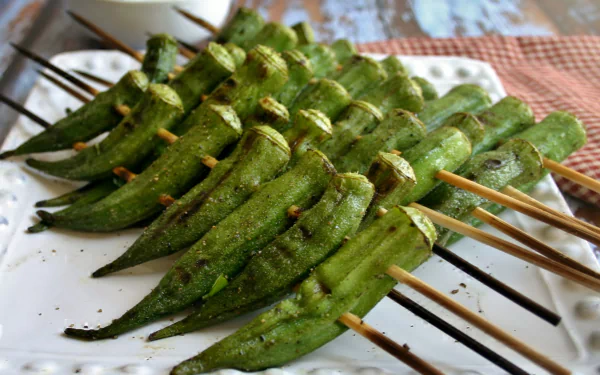 HD PC desktop wallpaper featuring skewered grilled okra arranged neatly on a white plate, highlighting vibrant green hues and a delicious food theme.