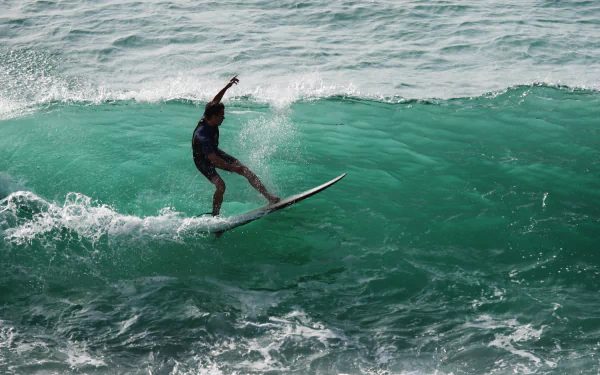 Surfer riding a wave on a clear ocean, captured in sharp detail for a 4K Ultra HD PC desktop wallpaper showcasing the thrill of surfing and sports.
