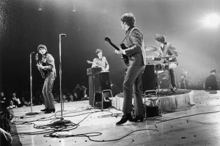 A captivating black and white image showcasing The Beatles—Paul McCartney, George Harrison, John Lennon, and Ringo Starr—performing live, radiating their iconic musical energy.