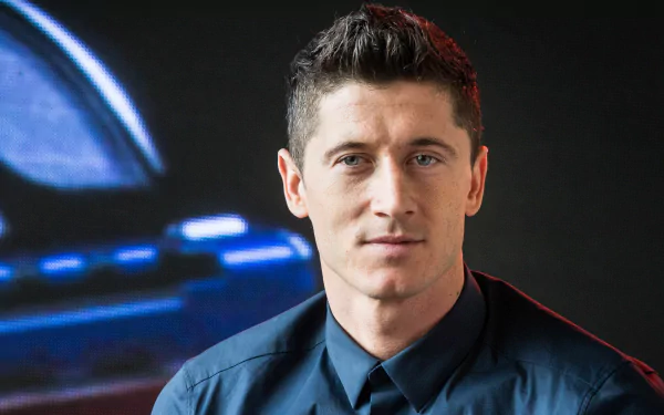 High-definition desktop wallpaper featuring Polish soccer player Robert Lewandowski in a blue shirt, captured against a dark background with a blurred blue and red light.