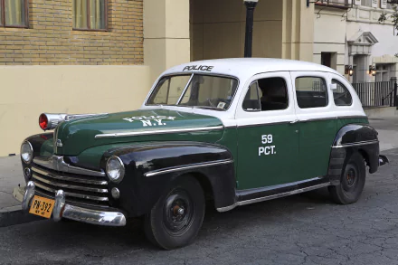 HD PC desktop wallpaper featuring a classic Ford police vehicle in green, black, and white parked on a city street, showcasing vintage law enforcement design.