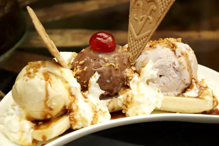 HD desktop wallpaper featuring a banana split with scoops of vanilla, chocolate, and strawberry ice cream, topped with wafers, a cherry, and whipped cream.