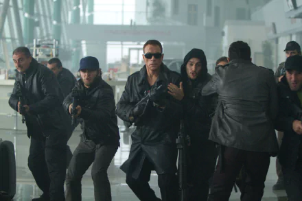 A high-definition wallpaper featuring Jean-Claude Van Damme as Vilain in The Expendables 2, surrounded by armed characters in an intense action scene.