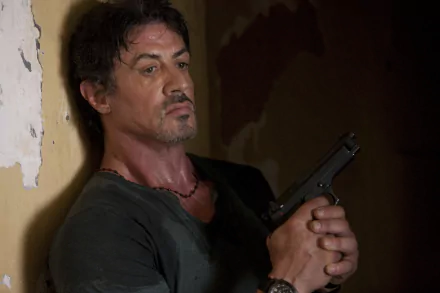 Sylvester Stallone as Barney Ross, gripping a handgun, in a dramatic moment from The Expendables. A striking 4K Ultra HD wallpaper background.