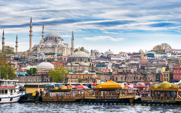 A vibrant HD wallpaper of Istanbul showcases the stunning skyline with domes and minarets, complemented by bustling boats along the water's edge and a dramatic sky overhead.