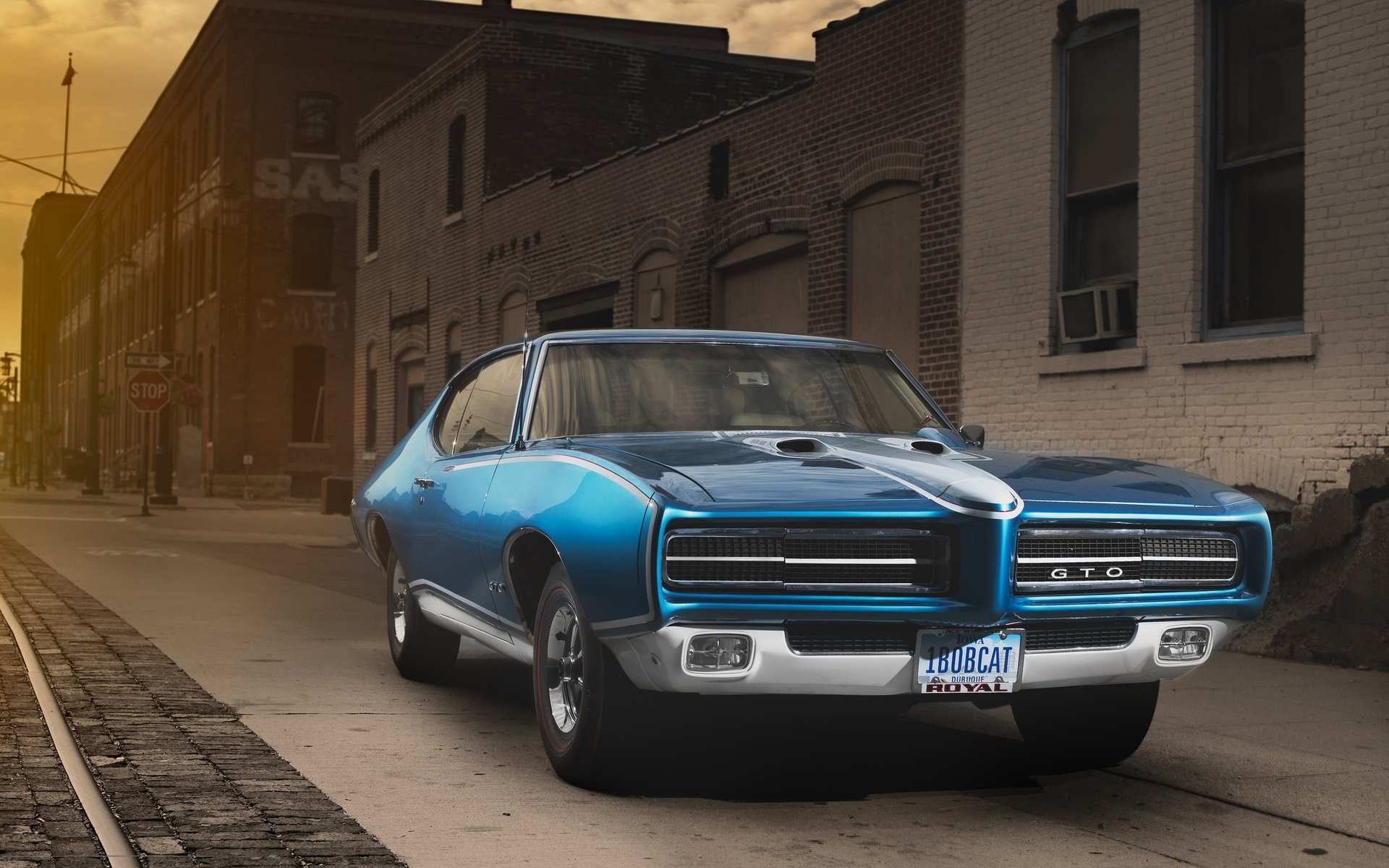 A blue Ford Torino GT parked on a city street at sunset, captured in high-definition as a PC desktop wallpaper background.