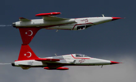 HD desktop wallpaper featuring two Northrop F-5 jet fighter warplanes with Turkish markings performing at an air show against a dark sky.