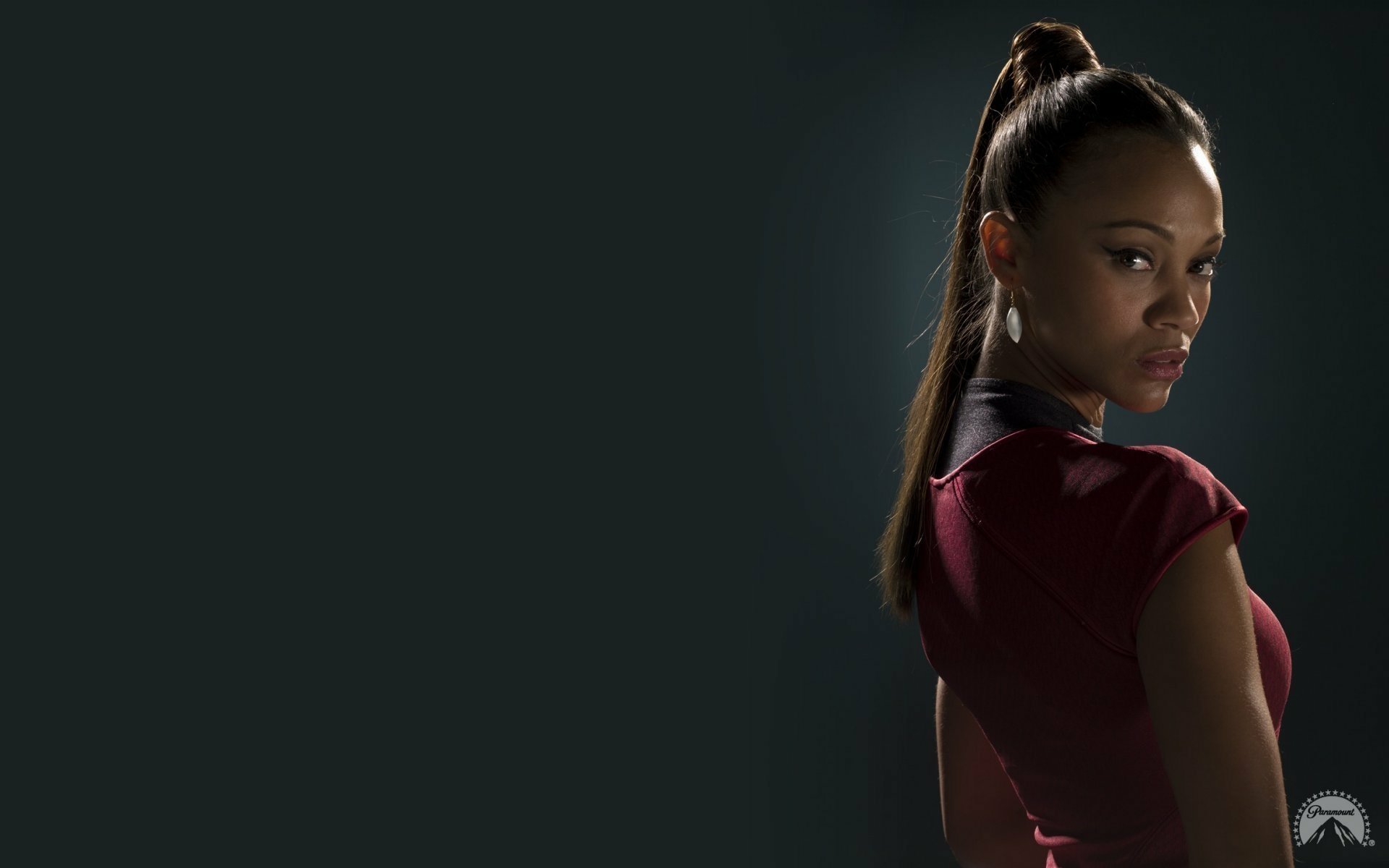 Zoe Saldana in a striking pose, dressed in Star Trek attire, features prominently in this HD wallpaper, showcasing her iconic role in the movie franchise.