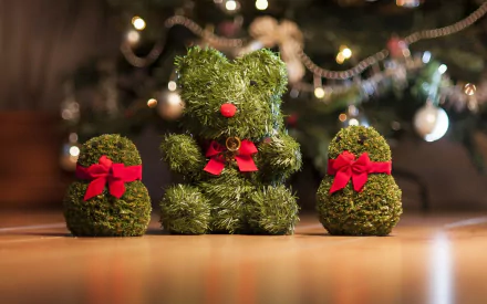 HD Christmas desktop wallpaper featuring a cute, humorous teddy bear and two small gift-shaped figures made of green foliage with red bows, set against a festive holiday background.