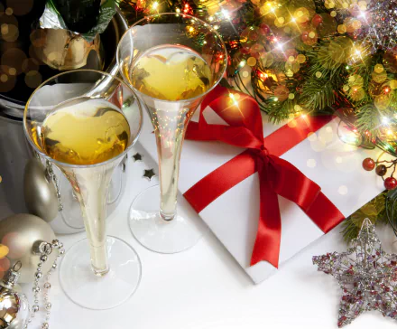 Two elegant champagne glasses filled with bubbly sit beside a beautifully wrapped holiday gift adorned with a red ribbon, set against a festive Christmas backdrop.