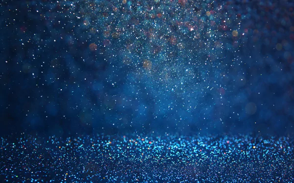 Abstract HD wallpaper featuring a captivating display of glittering particles against a deep blue background, creating an enchanting and shimmering visual effect.