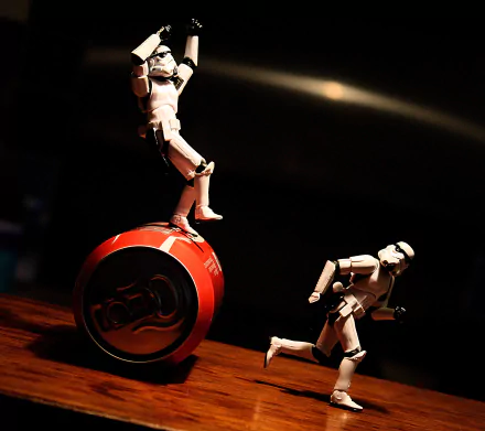 HD PC desktop wallpaper of Star Wars stormtrooper toy figurines in dramatic lighting — one balancing on a red yo-yo, another posed running; sci-fi themed background