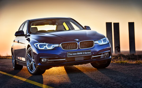 HD desktop wallpaper showcasing a sleek blue BMW 3 Series car illuminated by warm sunset lighting on an open road.