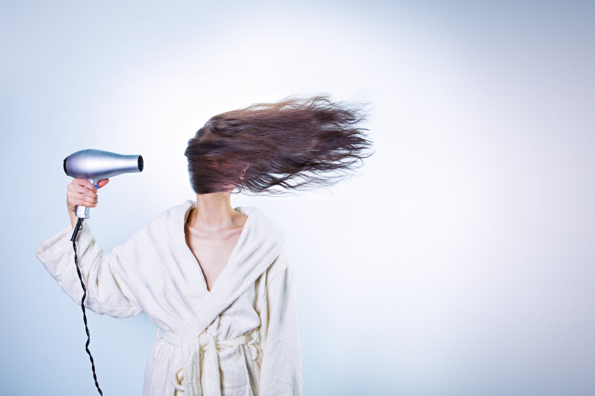 4K Ultra HD desktop wallpaper of a woman in a white robe using a hairdryer, with her hair dramatically blown to the side against a light background.