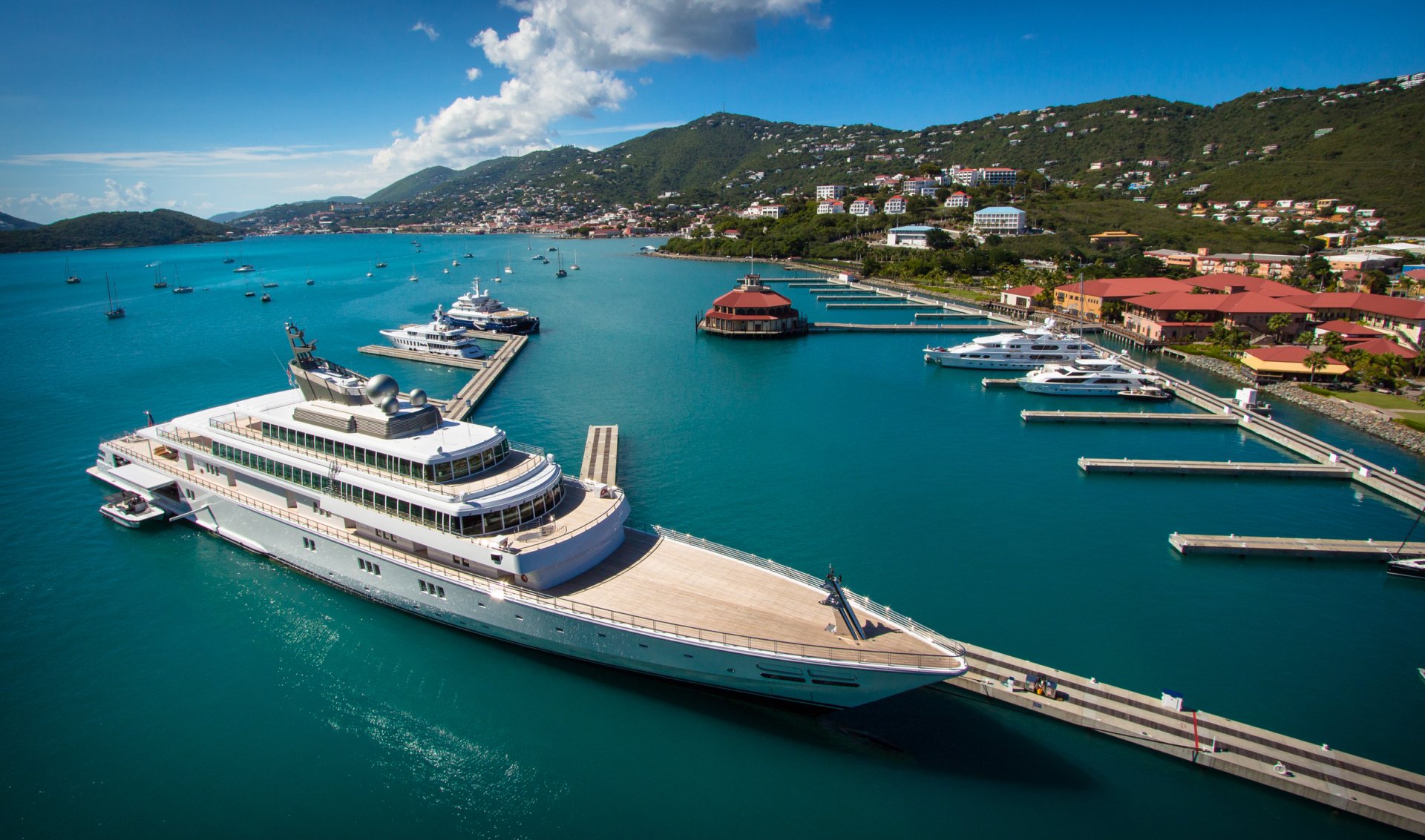 HD PC desktop wallpaper featuring a stunning aerial view of a yacht docked at a marina with clear blue waters and surrounding hills under a bright sky.