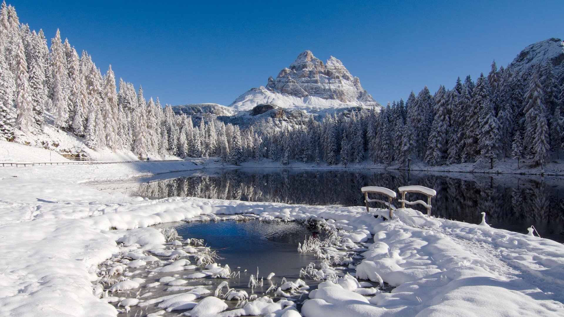 HD PC desktop wallpaper of a winter nature scene: a snow-laden forest and frozen lake beneath a towering snowy mountain.