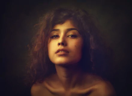 HD desktop wallpaper featuring a close-up of a brunette woman with brown eyes, showcasing a soft, expressive model face against a dark background.