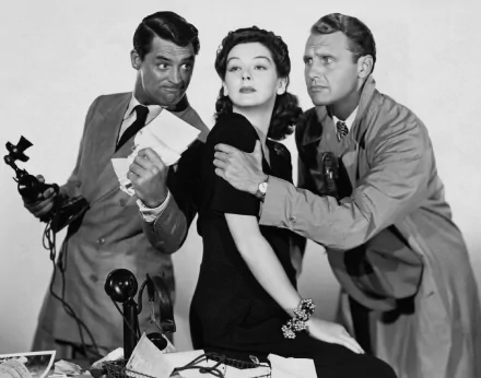 Black-and-white HD desktop wallpaper: film still from His Girl Friday — three actors in a tense newsroom pose, a woman flanked by two men, one holding a telephone.