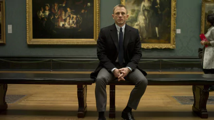 HD desktop wallpaper featuring Daniel Craig as James Bond from the movie Skyfall, seated in a museum setting with classic paintings in the background.