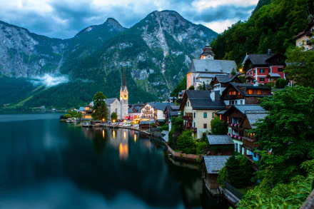 A stunning HD wallpaper of Hallstatt, Austria, featuring charming village architecture against a backdrop of mountains and a serene lake, evoking the beauty of man-made landscapes.