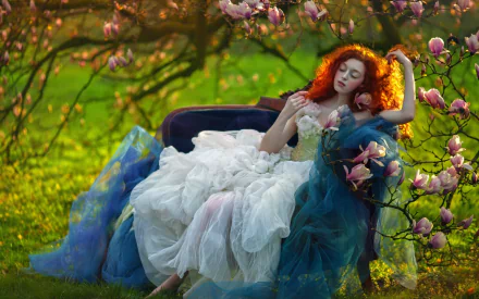 A redhead woman in a flowing white dress reclines on a chair beneath blooming magnolia branches in a serene, moody garden setting.