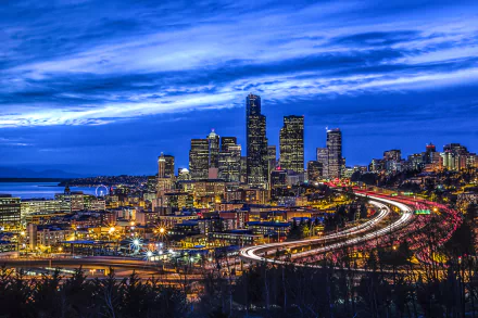 Time-lapse dusk cityscape of Seattle with bright city lights and streaks of vehicle lights, showcasing a vibrant man-made urban landscape in HD quality.