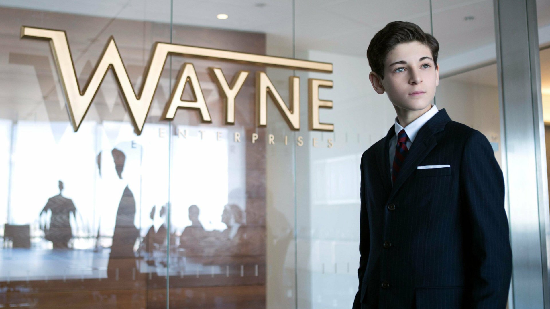 HD PC desktop wallpaper featuring a young character from Gotham TV Show standing confidently inside Wayne Enterprises lobby.